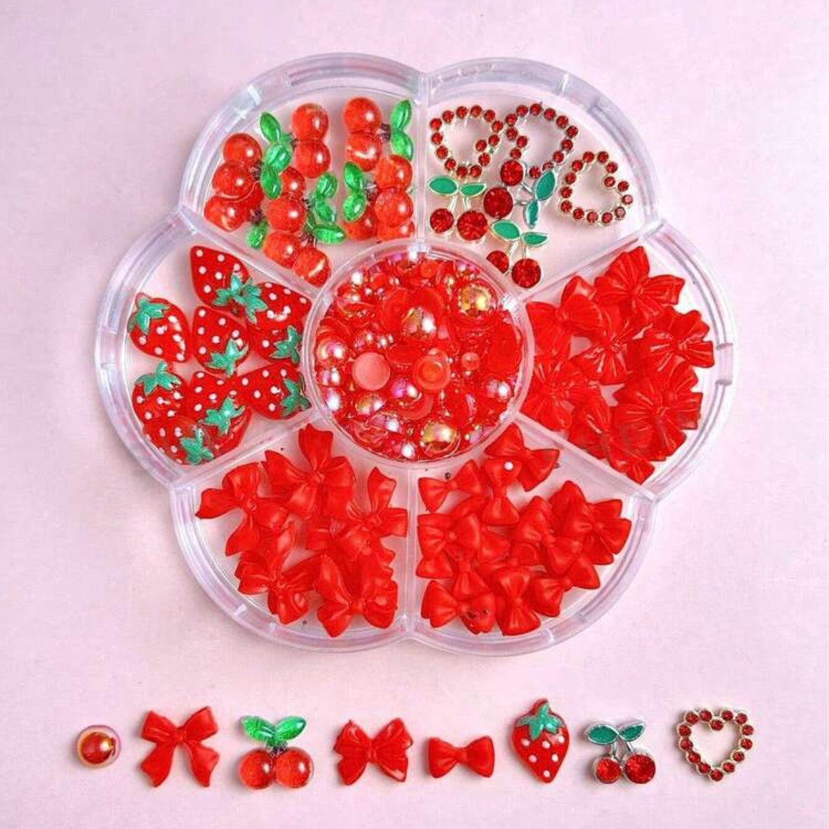 Clear plastic organizer with red decorative items on a light pink background