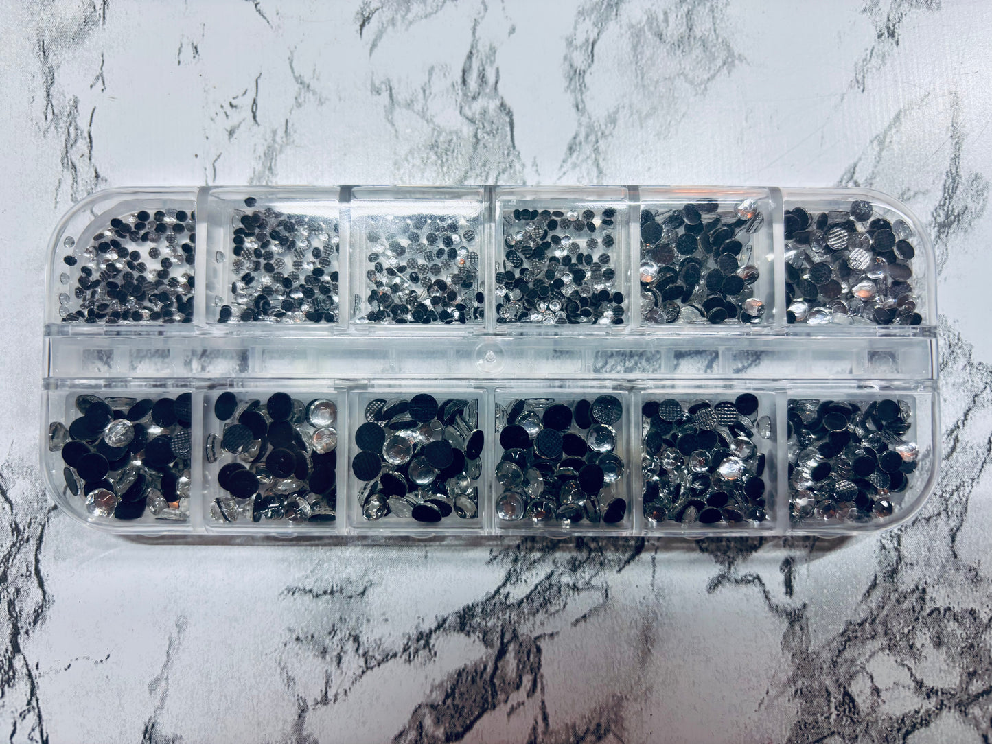 Clear container with black rhinestones on a marble surface