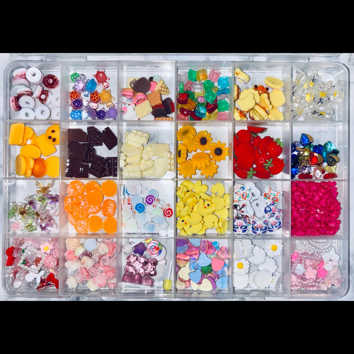 Assorted small decorative items in a clear organizer box.