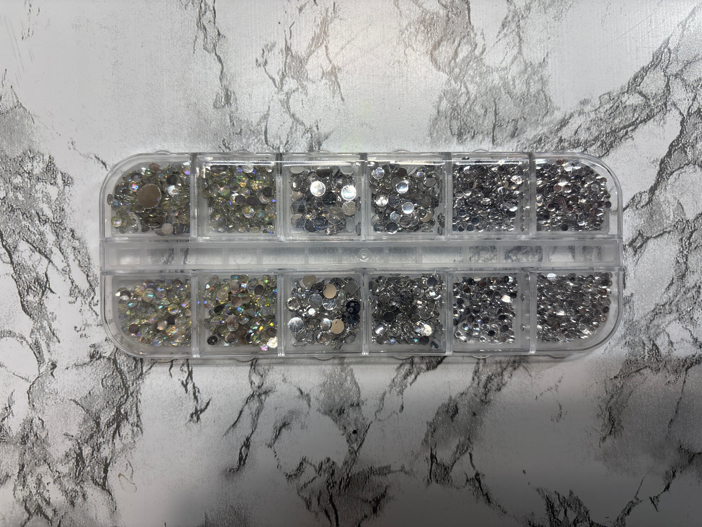 Container of rhinestones on a marble surface