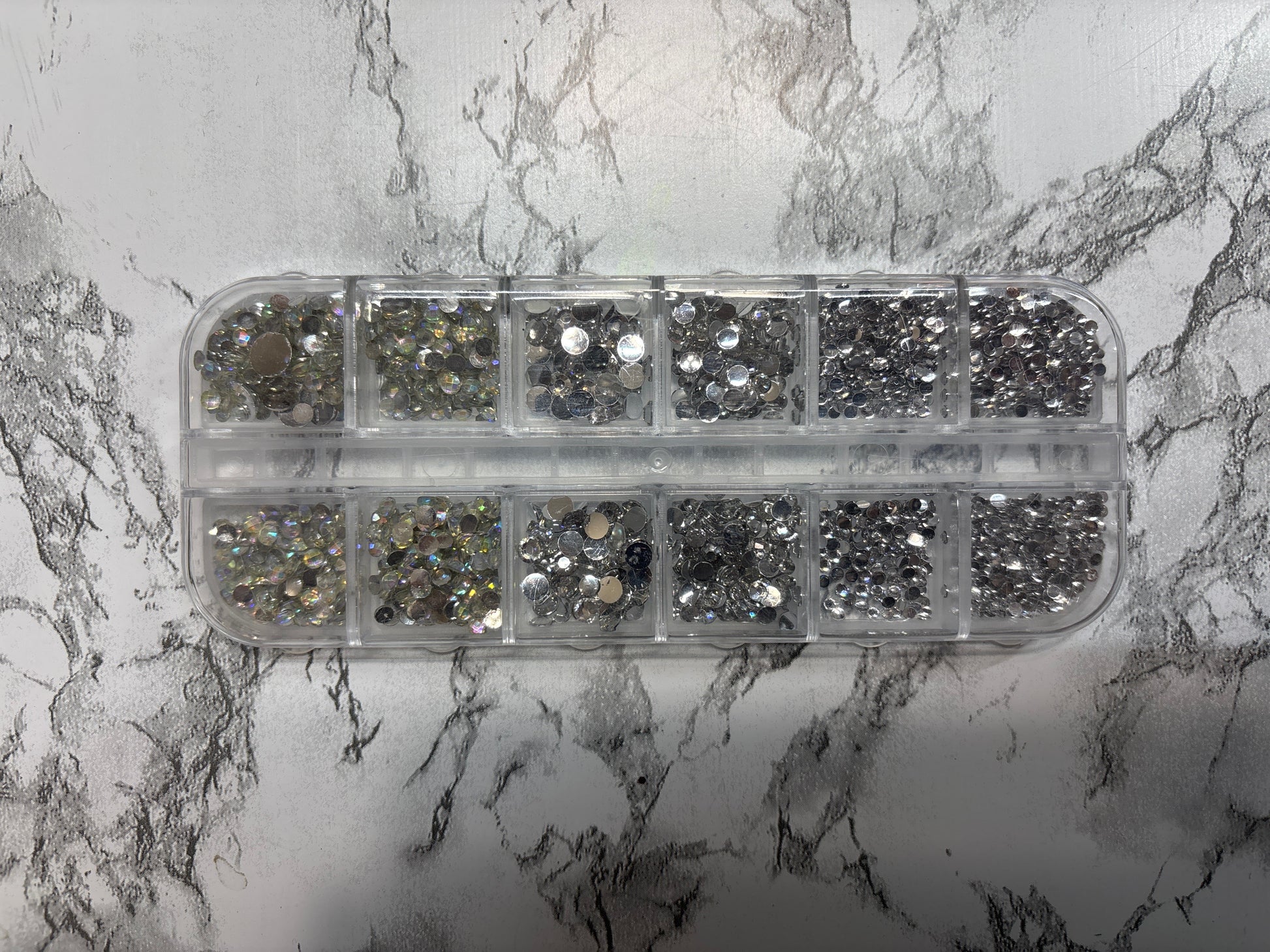 Container of rhinestones on a marble surface