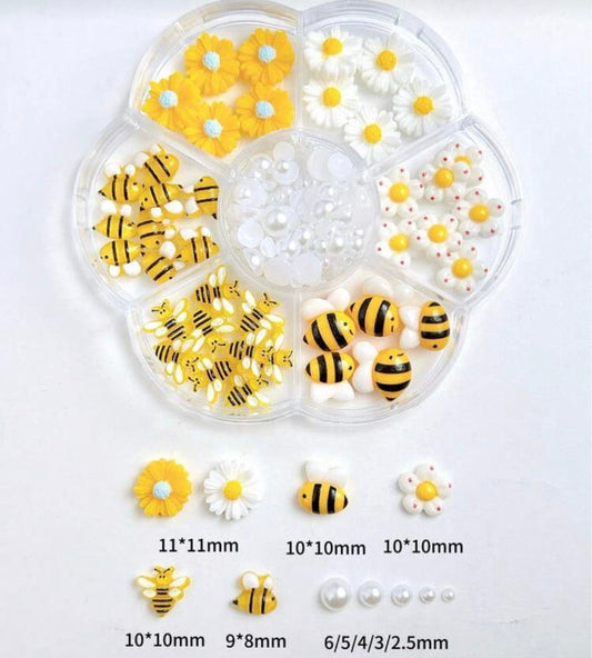 Set of bee-shaped beads and small white pearls in a clear plastic organizer on a light gray background.
