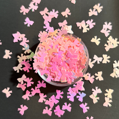 Pink bow-shaped confetti on a black surface