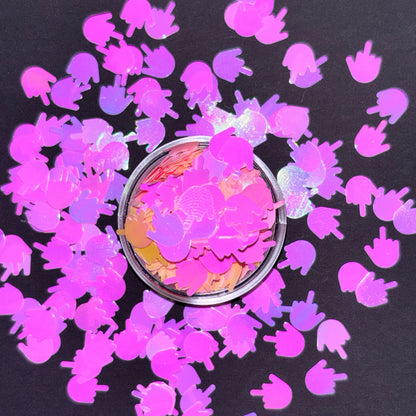 Pink glittery hand-shaped confetti around a small container on a black background