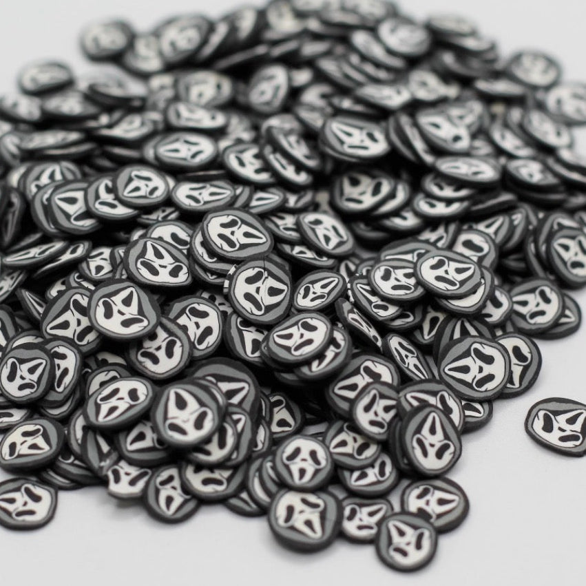 A pile of small oval black and white decals or stickers with a stylized face design, photographed on a plain light gray background.