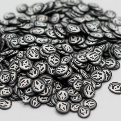 A pile of small oval black and white decals or stickers with a stylized face design, photographed on a plain light gray background.