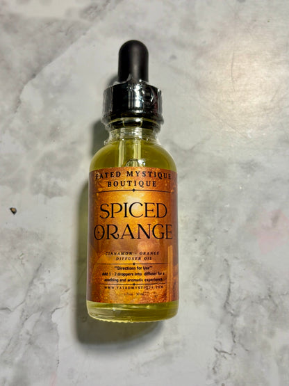 Bottle of 'Spiced Orange' diffuser oil from The Mystic's Spiced Orange boutique on a textured gray surface.