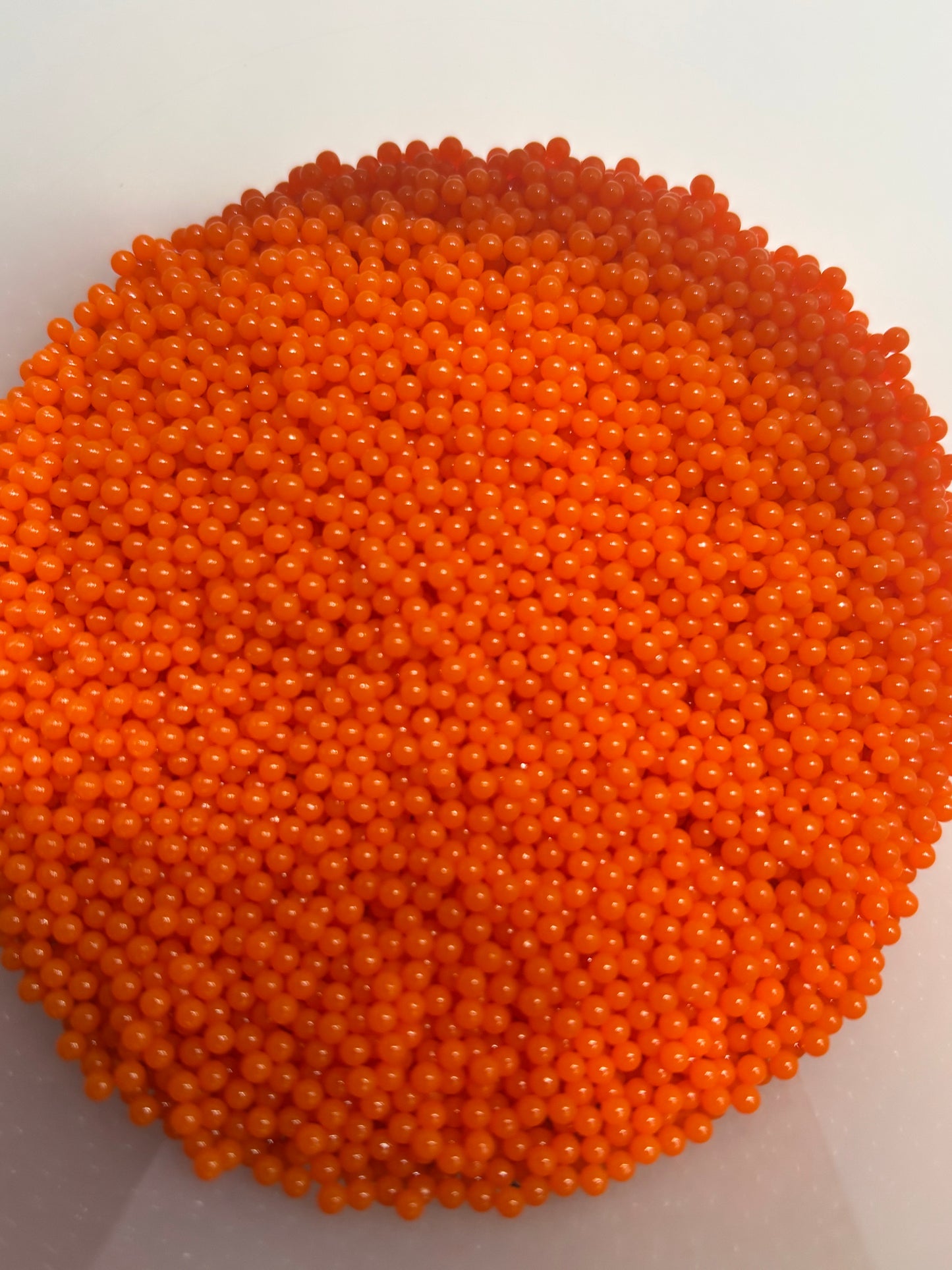 Close-up of orange beads in a white container