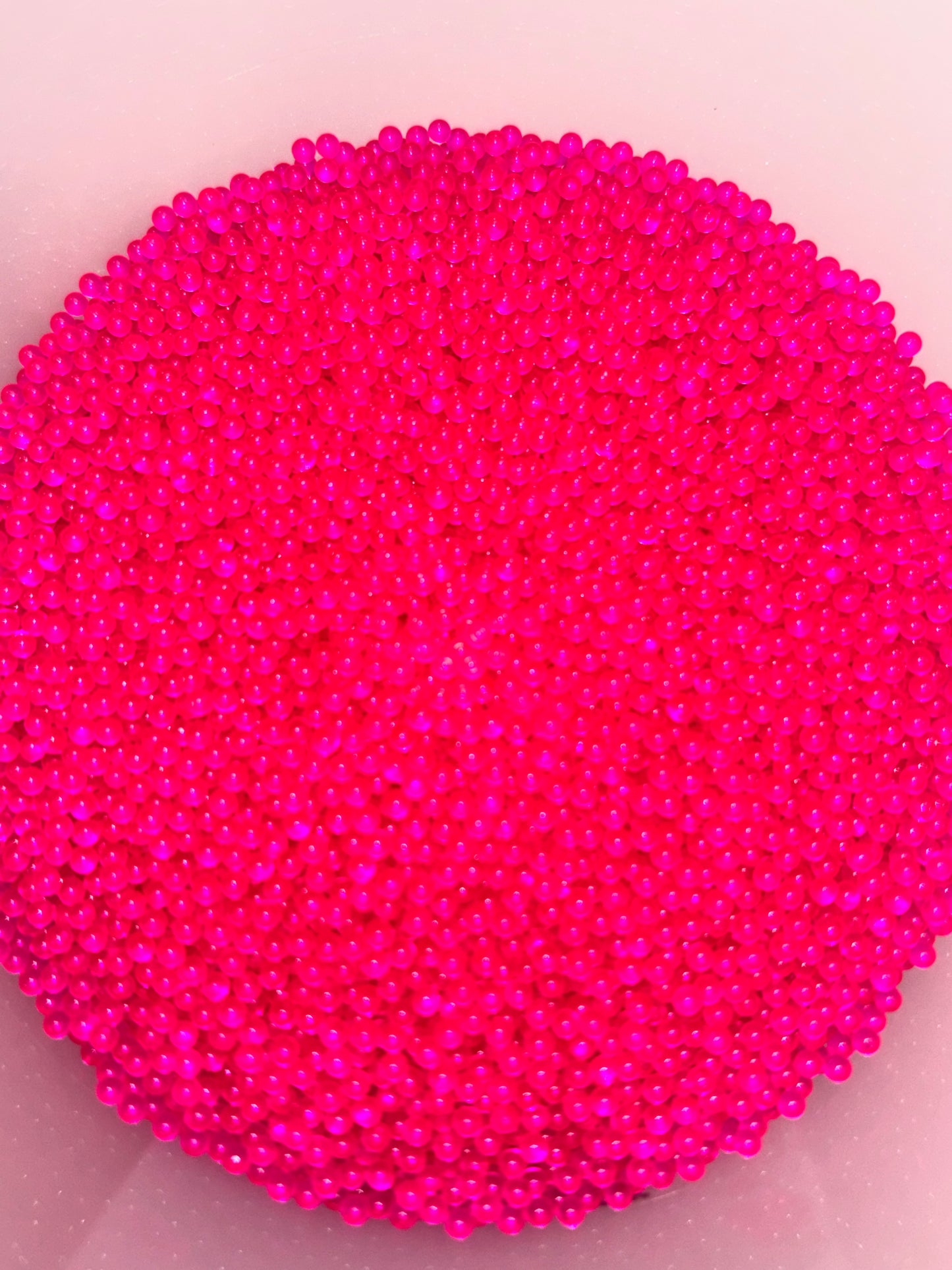 Close-up of bright pink beads on a light pink background