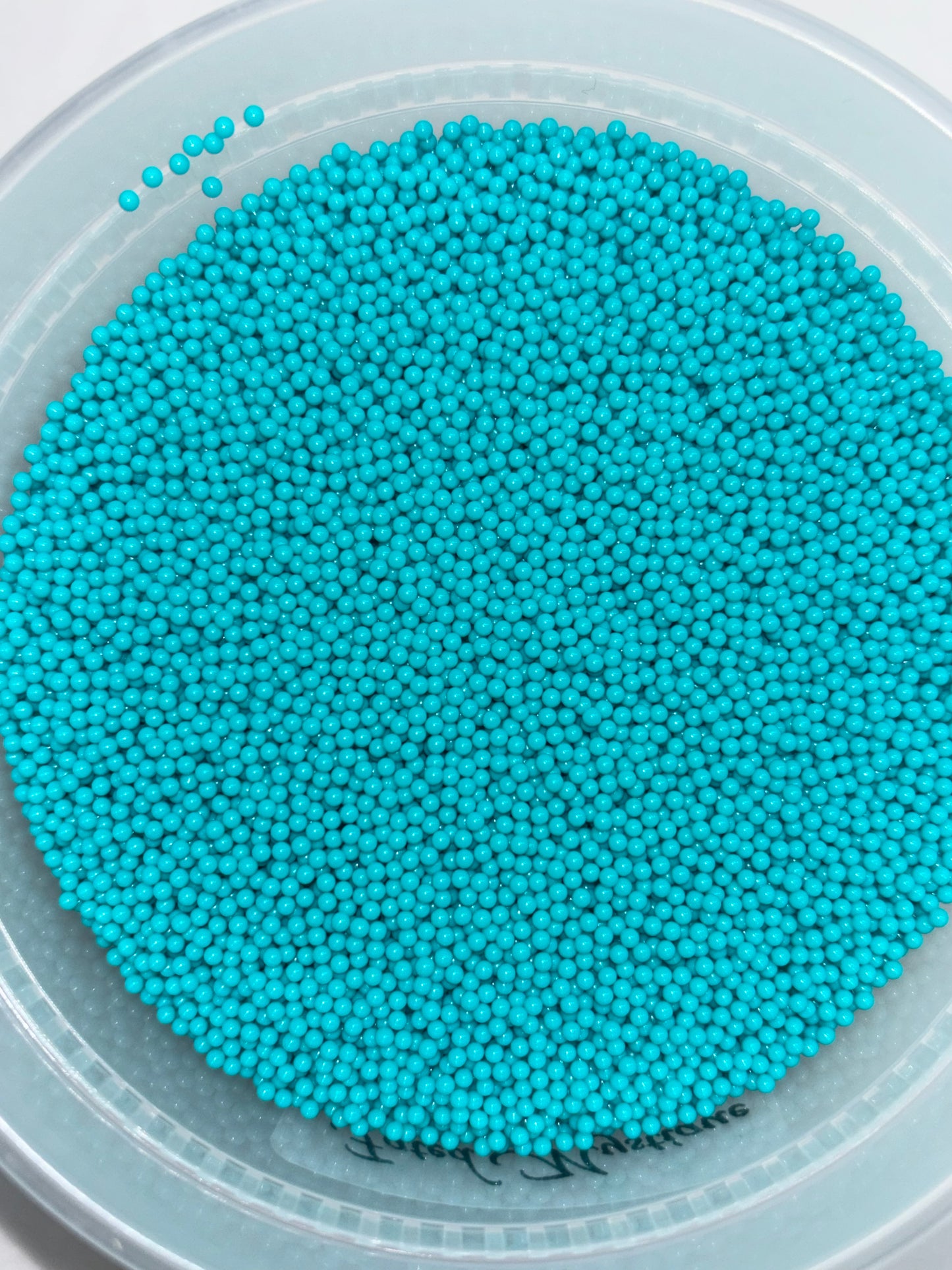 Turquoise beads in a clear container on a white background