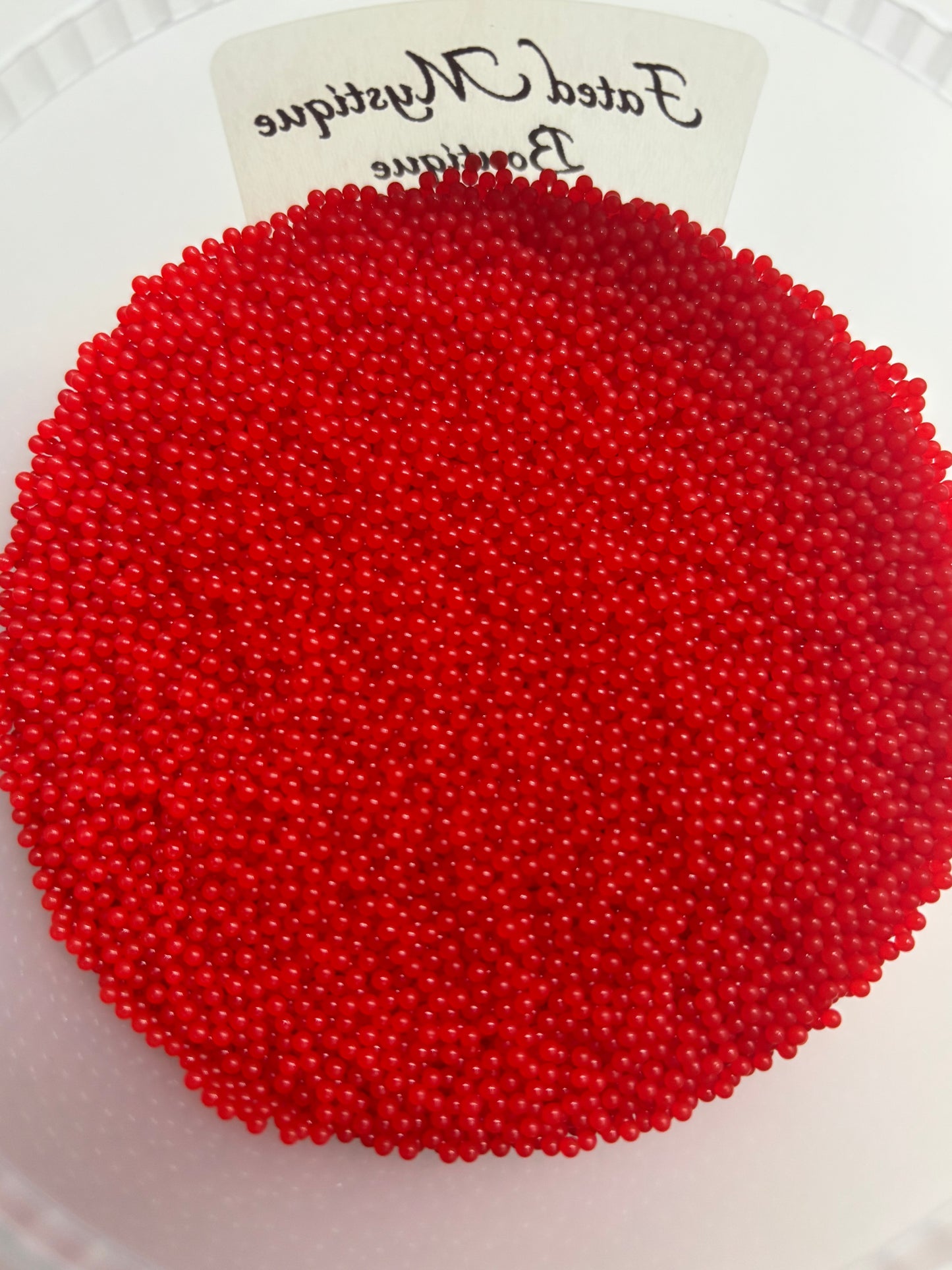 Red beads on a white plate with a label in the corner.