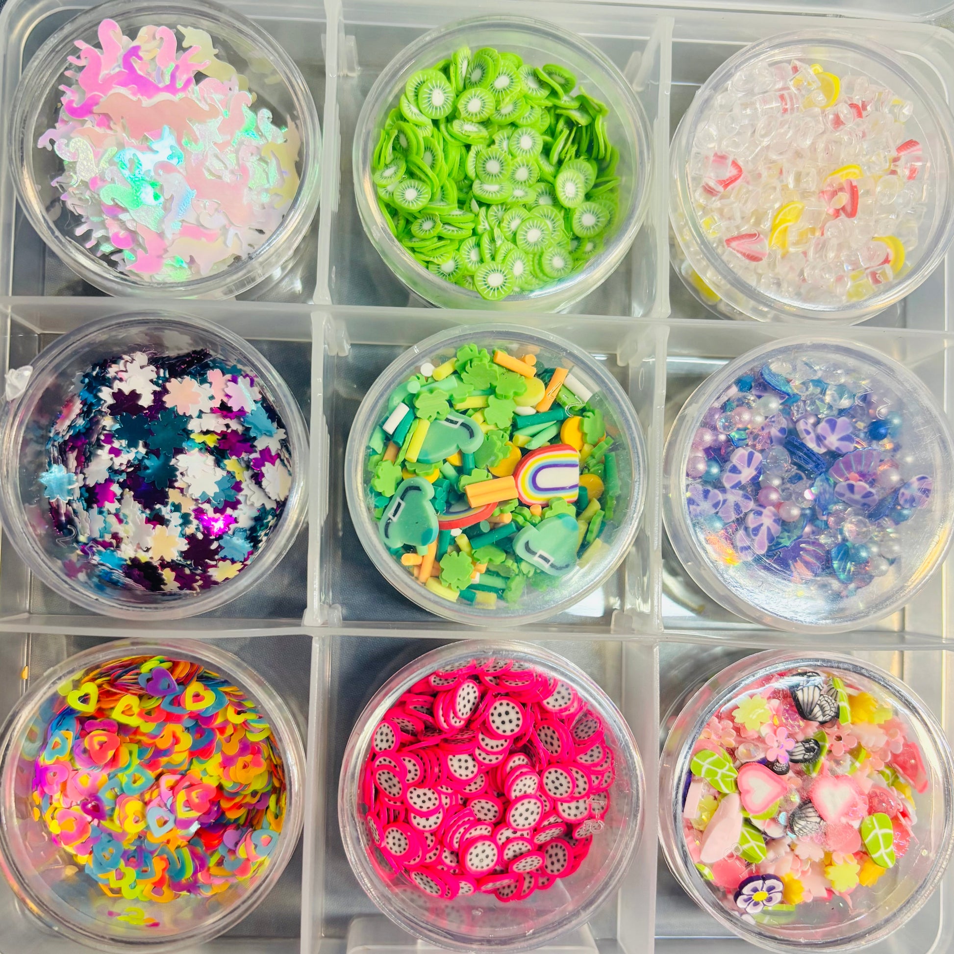 Assorted colorful embellishments in small containers inside a larger organizer.